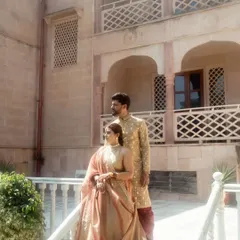A classic portrait of the couple on a balcony at their palace wedding venue. Their regal poses and coordinated outfits make for a timeless and elegant photograph.