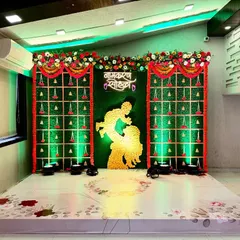 Honoring tradition with this beautiful Namkaran Sohala decor. The stage features a classic green backdrop with intricate genda phool (marigold) hangings and a central silhouette, creating a perfect setting for a traditional naming ceremony.