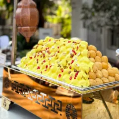 A mountain of fluffy Dahi Bhallas ready for a wedding feast. The soft lentil dumplings are topped with creamy yogurt, sweet and spicy chutneys, and pomegranate seeds, creating a refreshing and flavourful chaat.