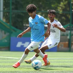 A player shields the ball from a defender, showcasing strength and control during a competitive U-17 league match.