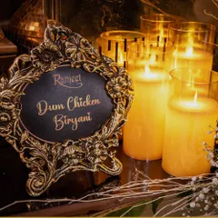The ambiance is set for a culinary classic. Our fragrant Dum Chicken Biryani, a perennial favorite at weddings, is presented with an elegant, candle-lit sign that adds to the luxurious feel.
