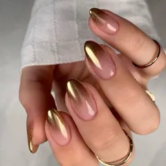 A sophisticated take on the metallic trend. This design features a beautiful gold-to-nude ombré on almond-shaped nails. The gold chrome at the tips gradually fades into a natural base, creating a chic and modern effect.