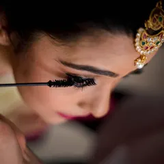 The final touch. A close-up shot capturing the moment the makeup artist applies mascara to the bride's lashes.