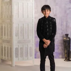 This is a sophisticated Indo-western outfit I created for an older boy. It features a heavily embellished black velvet jacket worn over an asymmetrical black kurta and trousers, ideal for a formal wedding reception.