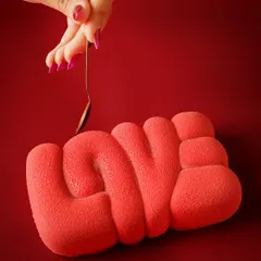 This 'LOVE' shaped dessert is a work of art. The clean, bold red background makes the unique texture and shape the absolute hero. This type of conceptual shot is perfect for seasonal campaigns, especially for Valentine's Day.
