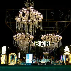 A stunning bar setup for a 25th-anniversary cocktail party, featuring a canopy of crystal chandeliers. This opulent design makes the bar a central and glamorous feature of the event.
