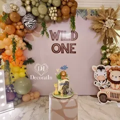 Roar! This "Wild One" safari theme is perfect for a little explorer's first birthday. The setup includes a full balloon arch with animal prints, cute jungle animal cutouts, and a large marquee '1' to mark the special milestone.