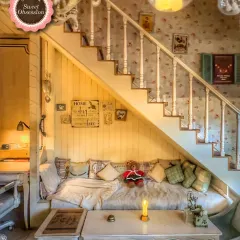 This is my cozy nook under the stairs, a favorite spot for many guests. It’s filled with soft pillows and has a warm, secluded feel, perfect for a dreamy date.