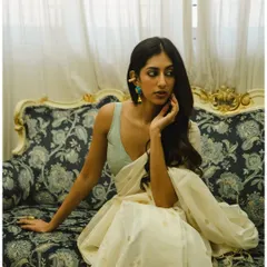 A classic three-quarter portrait on a vintage sofa. This shot highlights the graceful drape of the saree and the model's elegant posture.
