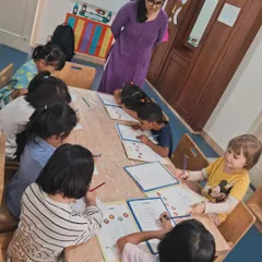 This image shows a focused group of pre-kindergarteners practicing their writing skills. I provide gentle guidance and support as they learn to hold a pencil and form shapes.