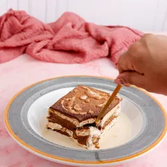 A classic tiramisu, showing its distinct layers of coffee-soaked ladyfingers and mascarpone cream.