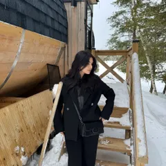Posing on the wooden steps of a barrel cabin, surrounded by a winter wonderland.