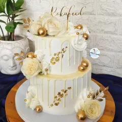 This two-tier Roka cake is all about classic elegance. I used a white-on-white drip effect, delicate white roses, and touches of gold leaf and spheres to create a timeless and luxurious look.