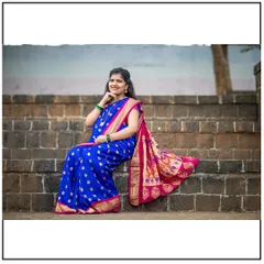 A graceful portrait of a mom-to-be seated on stone steps, her royal blue Paithani saree beautifully displayed.