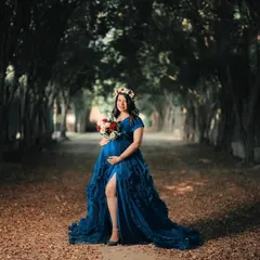 A breathtaking fairytale maternity portrait of a woman in a flowing blue gown, standing in a majestic tree-lined pathway. This shot is all about creating a sense of wonder and drama.