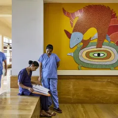 Informal interactions in a sunlit corridor of the JSW Sanjeevani Hospital. We design these transitional spaces to be wide and comfortable, with built-in seating to encourage moments of rest and conversation for staff and patient families.