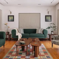 In our Cocoon House project, we curated a living space that feels both sophisticated and deeply personal. The design blends a rich emerald sofa and a patterned armchair with bespoke wooden coffee tables, all grounded by a colorful geometric rug, creating a space that is layered with character and comfort.