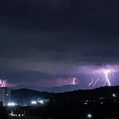Multiple forks of lightning strike behind the hills in Pune, creating a spectacular natural light show.