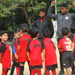 My coaches and I gather our youngest players for a quick team talk. I make sure to create a supportive environment where even the smallest players feel heard, valued, and excited to learn.
