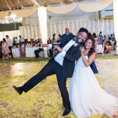 Pure, unadulterated fun on the dance floor. This candid shot captures the groom's playful energy and the couple's laughter, surrounded by a carpet of flower petals.