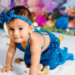 A close-up portrait from the mermaid-themed shoot, capturing her curious expression and the details of her sparkling blue costume and headband.