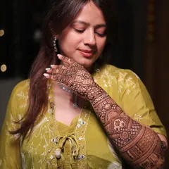 A quiet moment of reflection for the bride, her beautiful full-arm mehendi on display.