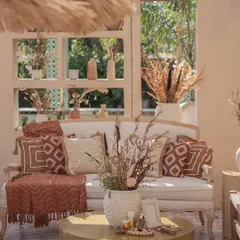 A cozy seating nook within the Desert Oasis theme. The white sofa is styled with rustic, patterned cushions and a throw, surrounded by dried floral arrangements and natural textures.