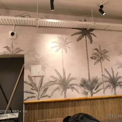 A wide shot of the cafe wall, highlighting the large-scale tropical mural. This kind of feature wall makes a commercial space memorable.