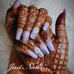 A beautiful bridal set featuring long, square-shaped lavender nails. The design is elevated with silver glitter, rhinestone accents, and delicate 3D white flowers, all set against beautiful bridal henna.