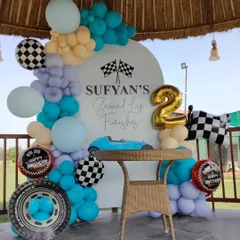 A "Second Lap" car racing theme for a 2nd birthday, set up outdoors under a gazebo. This decoration features a custom backdrop, a balloon garland, and racing-themed props like checkered flags and a tire balloon.