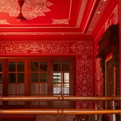 Looking up inside the red temple, the ceiling becomes a canvas of its own. Every surface, from the walls to the ceiling, was meticulously hand-painted, wrapping the space in a continuous story of devotion and artistry. The detail work softens the bold color, creating a serene atmosphere.