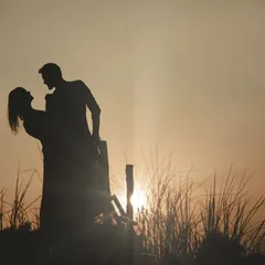 A classic romantic silhouette against a golden sunset, capturing the couple in a timeless dance pose.