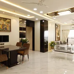 A wide-angle view of a completed 4BHK living room in Malad, featuring a central dining area and a separate lounge space with an acrylic swing. The glossy marble floors and extensive ceiling lights enhance the sense of luxury and space.