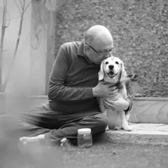 A touching black and white photo of a man kissing his senior Beagle, Leo, on the head, capturing a moment of deep love and companionship.