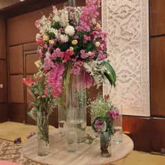 A beautiful and tall floral centerpiece for a guest table or entrance lobby. This arrangement uses a mix of lilies, carnations, and chrysanthemums in tall glass vases for a dramatic effect.