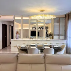 This dining space is defined by a stunning crystal chandelier that adds a touch of sparkle. Mirrored panels behind the console reflect light and create an illusion of spaciousness, making the area feel both glamorous and open.