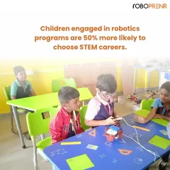 Young students collaborate around a table, working together on a robotics project. This hands-on experience is why children in our programs are more likely to choose future careers in STEM fields.