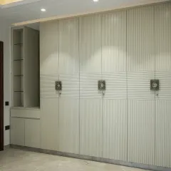 This elegant, floor-to-ceiling wardrobe integrates seamlessly into the room, featuring a built-in vanity with glass shelves for display.