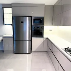 We design for complete functionality. This view shows the tall unit housing a built-in oven, microwave, and a side-by-side refrigerator, all perfectly integrated within the sleek, uniform cabinetry for a clean, uncluttered look.