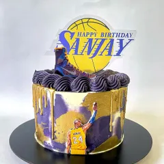 A tribute to the legend, Kobe Bryant. This Lakers-themed cake features the iconic purple and gold, a gold drip, and edible images of Kobe, his shoe, and a custom birthday topper. Mamba forever.