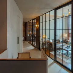 The corridor of the One Place Lodha office, featuring warm wood paneling and glass walls. This design creates a sense of flow and connection between different zones while maintaining a sophisticated and cohesive look.