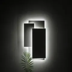 This modern wall light features overlapping geometric panels with backlighting. It functions as both a light source and a piece of abstract wall art, creating dramatic shadows and a sophisticated mood.