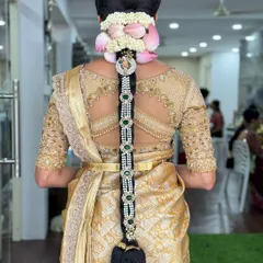 An exceptionally detailed bridal braid featuring strings of pearls, lotus-petal-shaped fresh flowers, and a jeweled centerpiece. This is a true statement hairstyle.