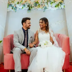 Hanish and Gloria share a sweet moment on a beautiful pink sofa during their Catholic wedding reception. The setting is as beautiful as their smiles.