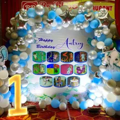 A closer look at the elephant theme first birthday backdrop, highlighting the custom photo collage and cute elephant cutouts on either side of the balloon arch.
