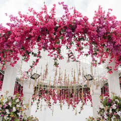 A close-up of the bougainvillea and hanging golden tassels on the floral arch. The combination of bright flowers and delicate traditional elements creates a rich, festive look.