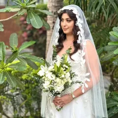A portrait of a gorgeous bride for her Goa wedding. Her hair is styled in soft, romantic waves that cascade beautifully under a delicate, leaf-patterned veil, creating a truly ethereal look.