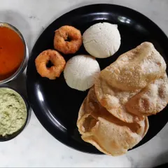 A plate of our delicious breakfast spread at the Nandi Hills resort, featuring idli, vada, and poori. A hearty start to a day of adventure.