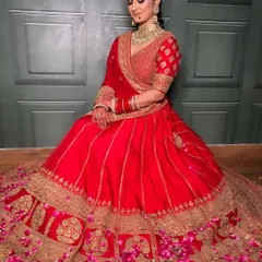 A bride surrounded by petals, looking absolutely pure and gorgeous. This full-length shot showcases her magnificent red and gold lehenga and the complete, regal look I created for her.