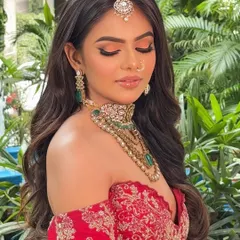 The same bridal look with eyes closed to showcase the beautiful peachy-orange eyeshadow blend. This adds warmth to the look and complements the red outfit perfectly.